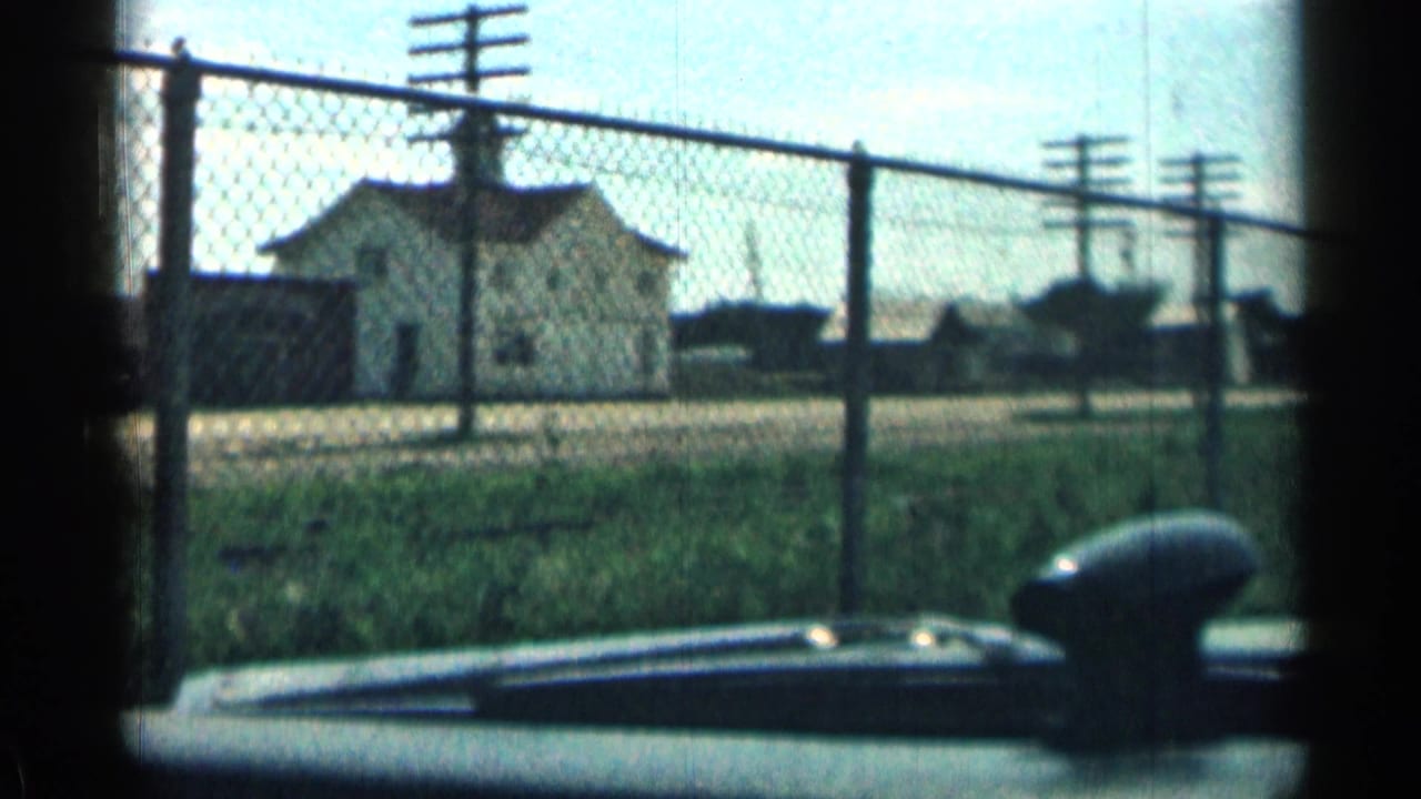 Chain-link fence and small building viewed from inside a car.