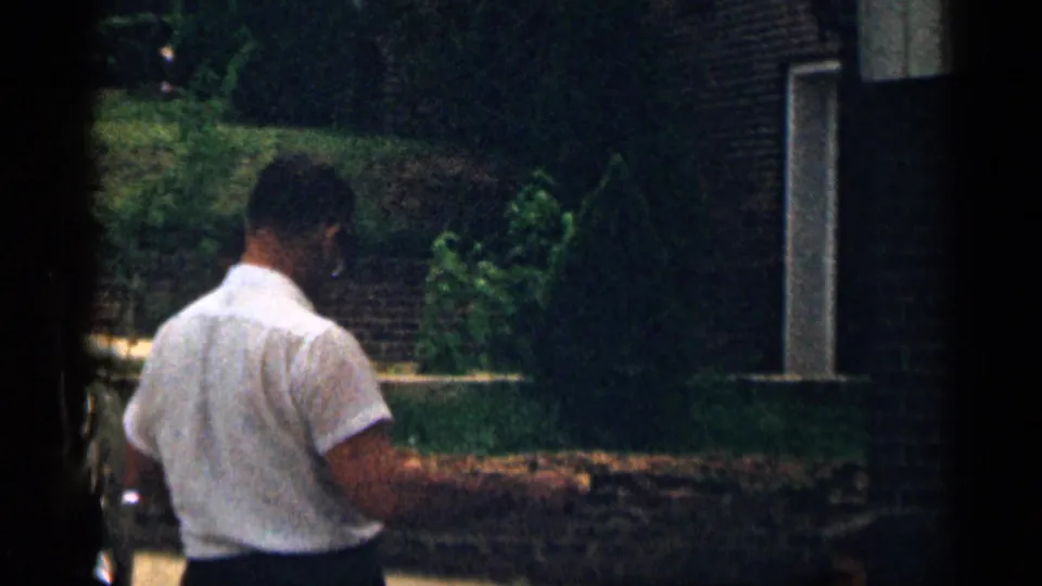 Adult man in white shirt seen from behind in a suburban Texas outdoor setting, 1963 home-movie footage.