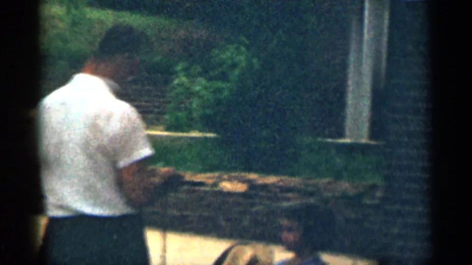 Adult man in a white shirt appears to hold a rope or leash near a residential exterior in 1963 Texas footage.