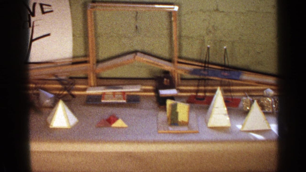Tabletop display of wooden geometric models against a green wall.