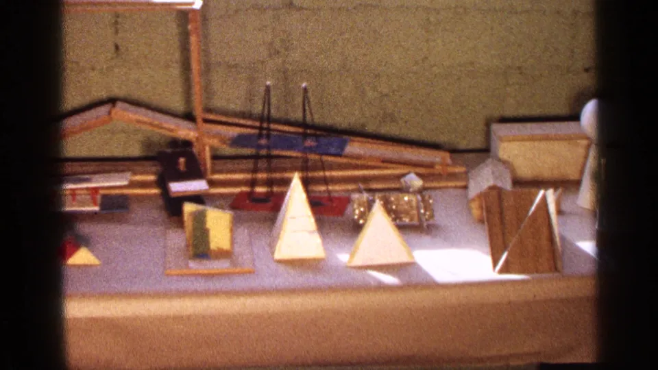 1963 Texas 8mm still showing the display from farther right, with pyramids, rods, colored blocks, and a standing wooden panel.