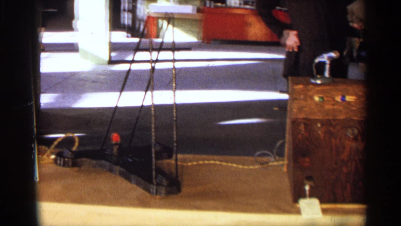Tripod stand and floor cables near a wooden display case in an interior room.