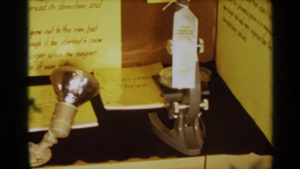 Detail of a 1963 Texas science fair project showing a microscope, award tag, handwritten notes, and display board edges.