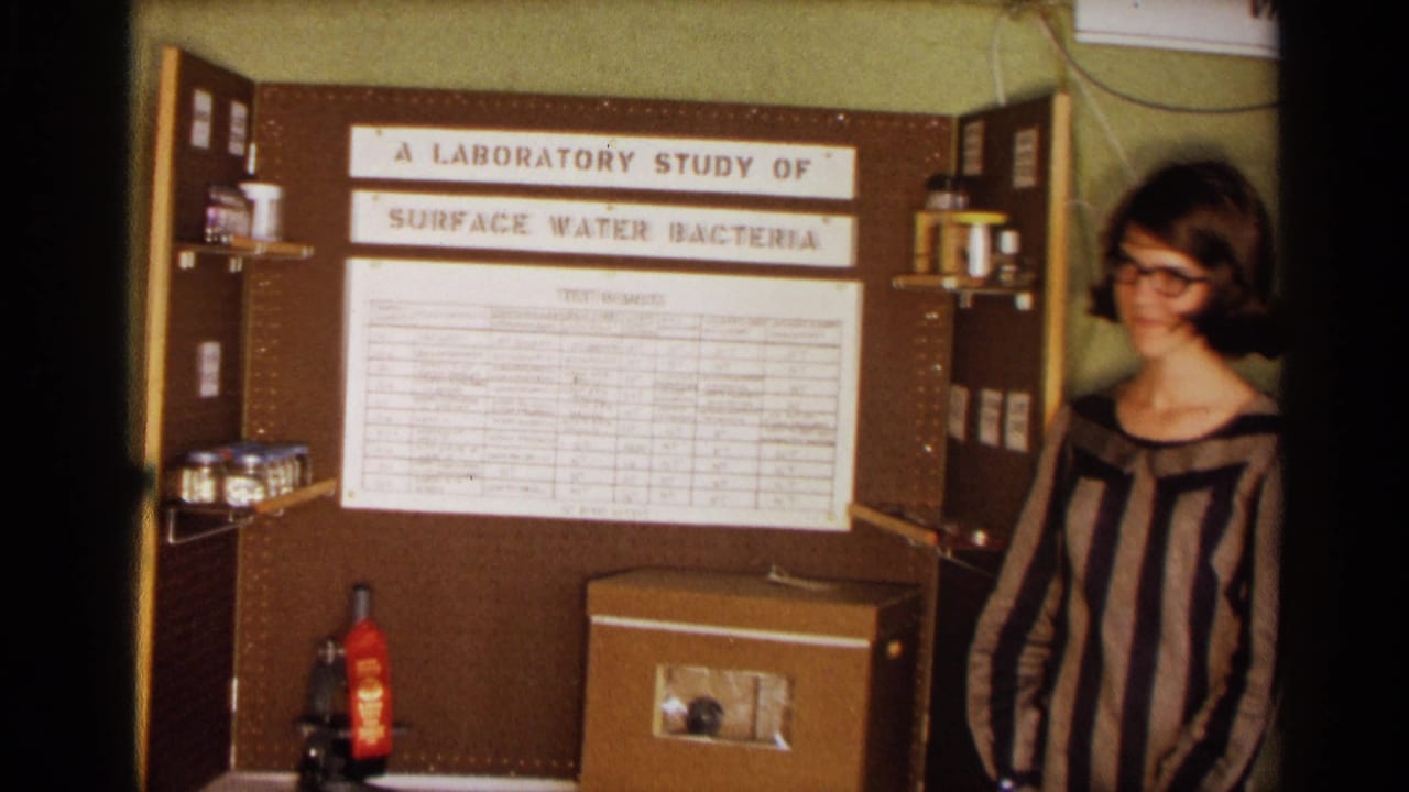 Science fair board with test results and a student standing at the right edge.