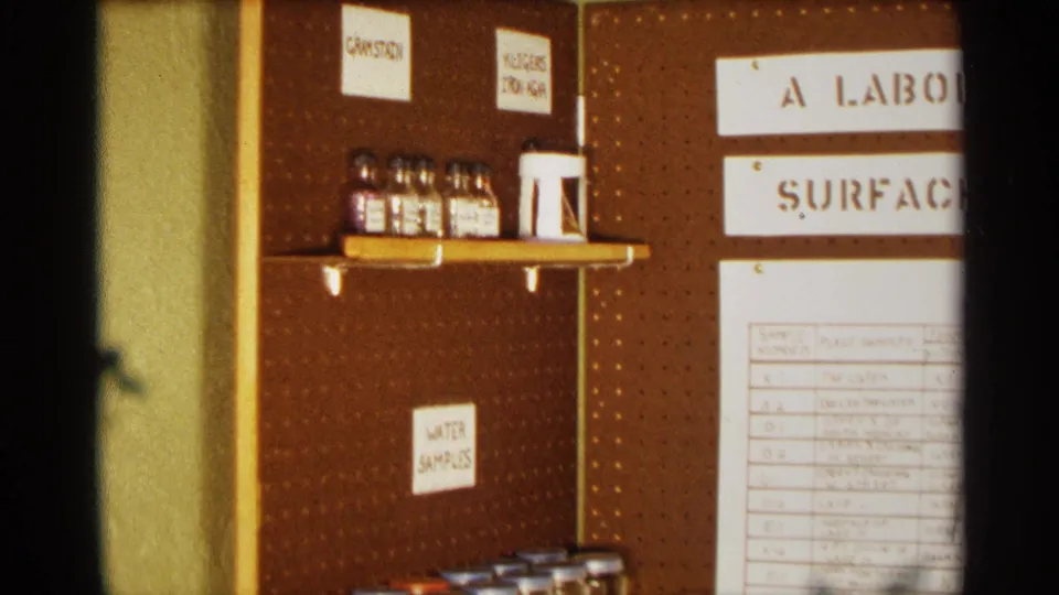 A closer view shows the project display's pegboard, labeled areas, small bottles on a shelf, and part of the surface water bacteria chart.