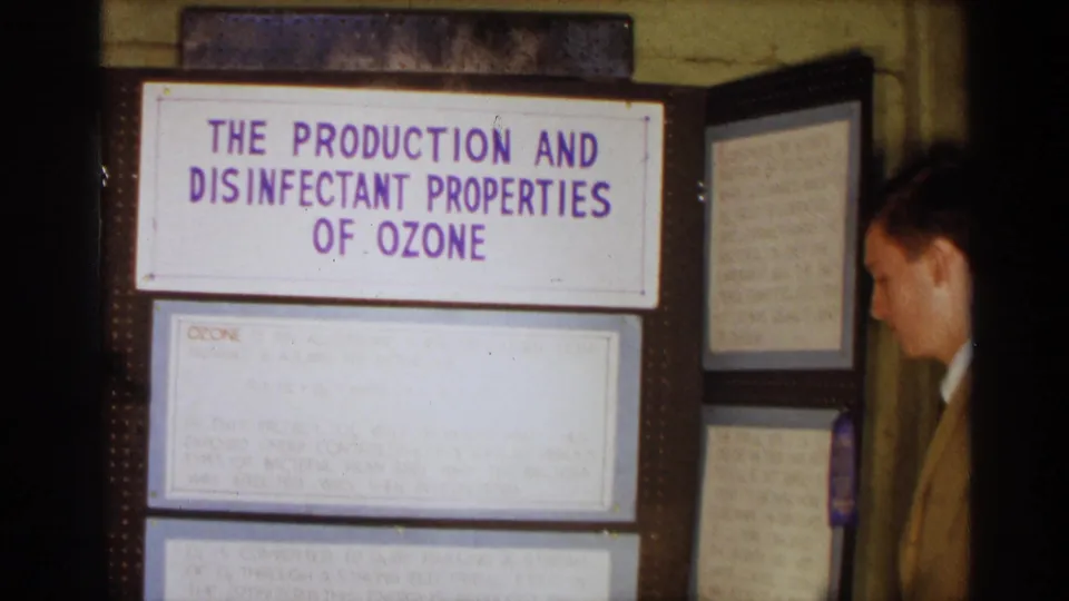 1963 Texas frame of a student science fair board titled The Production and Disinfectant Properties of Ozone, with notes and a person nearby.