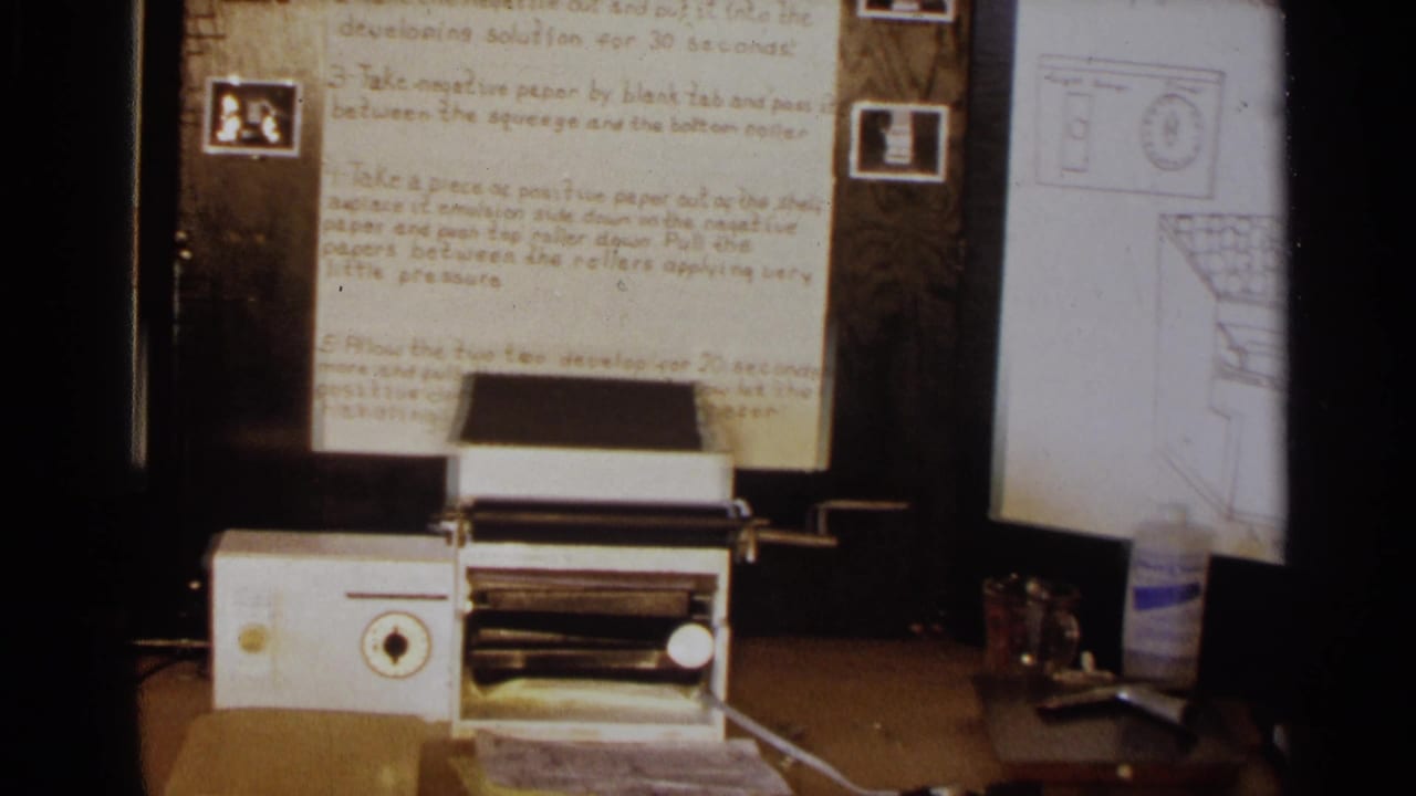White tabletop machine in front of handwritten instructions on a wooden display board.