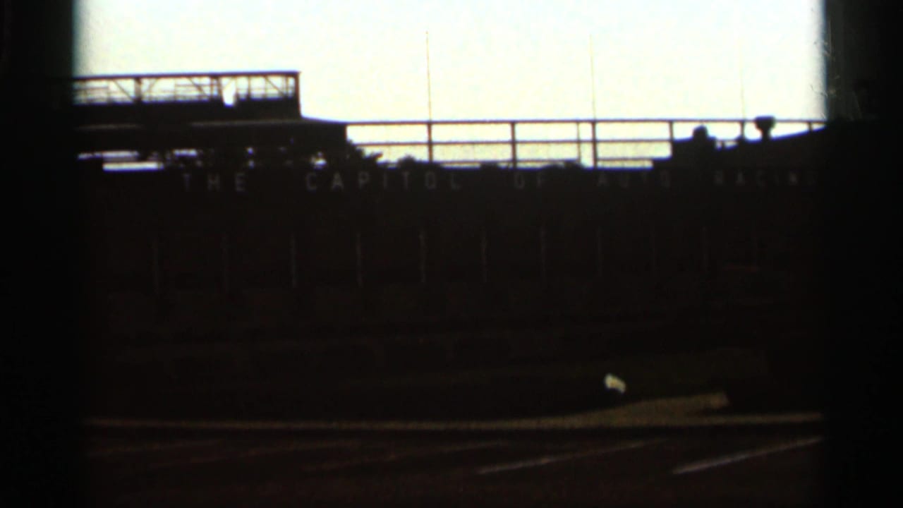 1964 8mm view at Indianapolis Motor Speedway showing a silhouetted grandstand structure against bright sky.