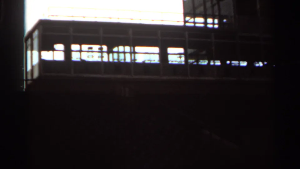 Low-angle 1964 8mm view of empty Indianapolis grandstand seating and railings in strong backlight.