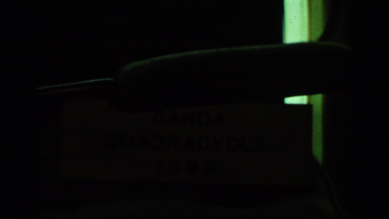 Dark close view of a sign or plaque with faint Canda Quadracycle lettering.