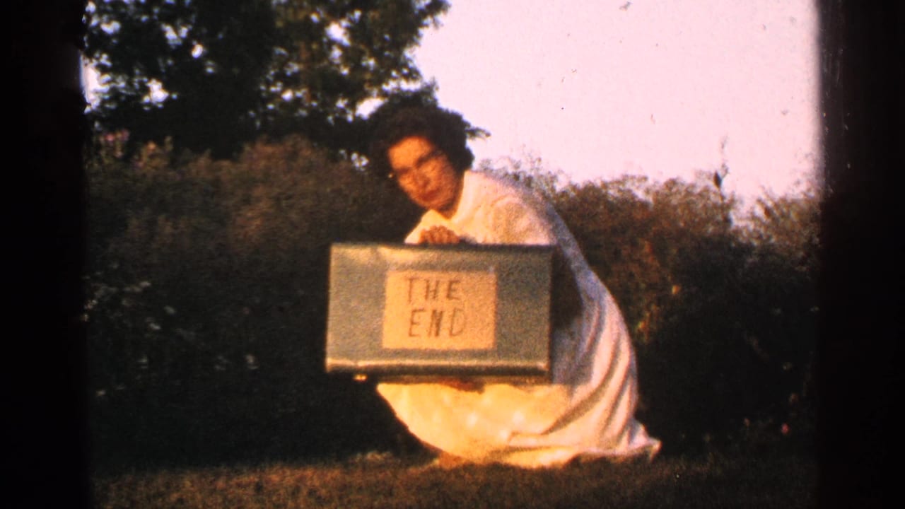 Woman kneeling and holding a green case labeled THE END.