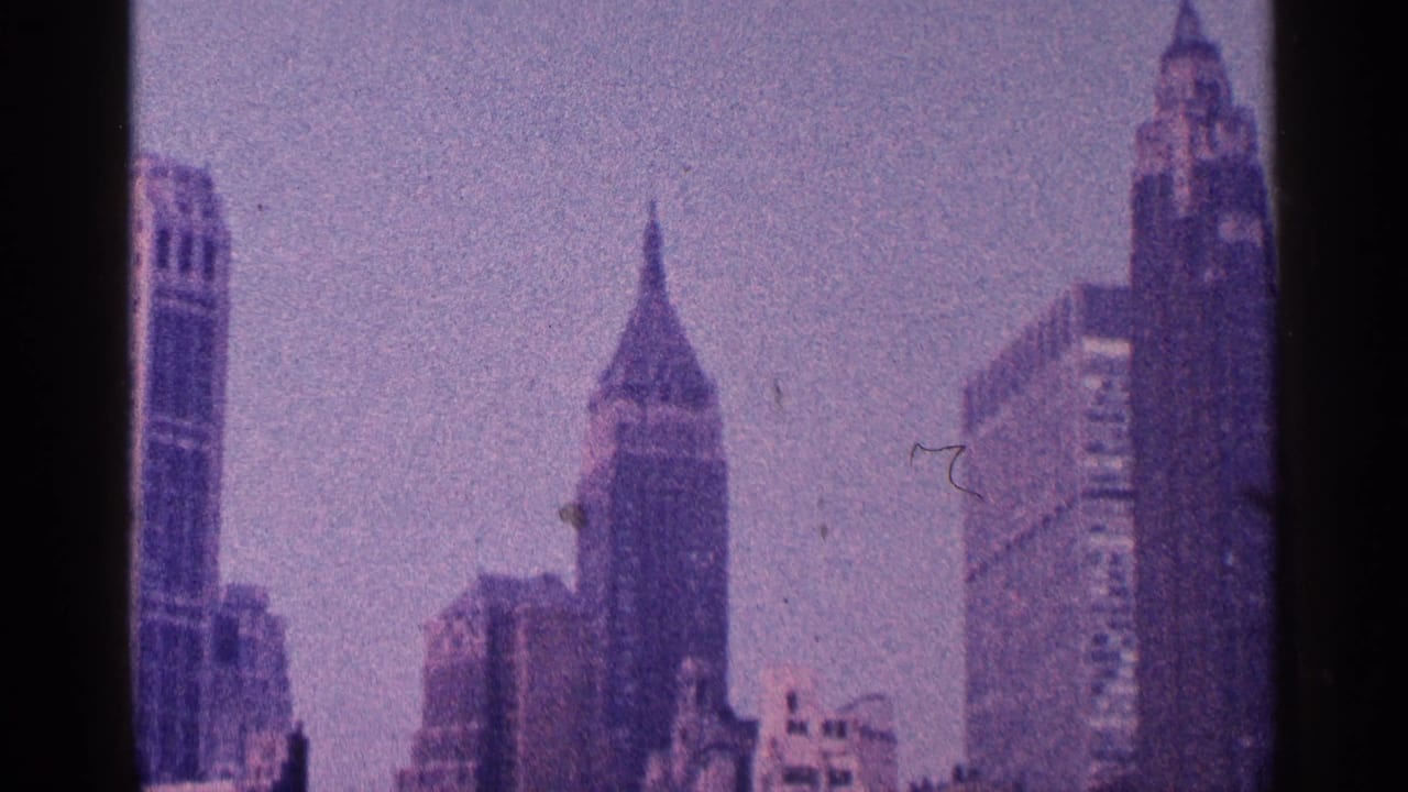 1964 New York City skyline view with Art Deco towers, hazy sky and a dark vertical film-gate band.