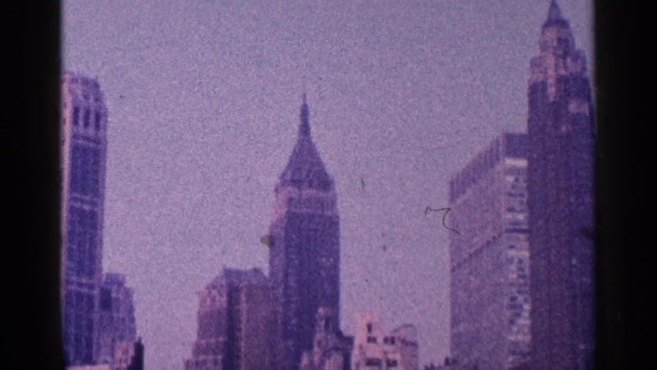 1964 New York City skyline view with Art Deco towers, hazy sky and a dark vertical film-gate band.