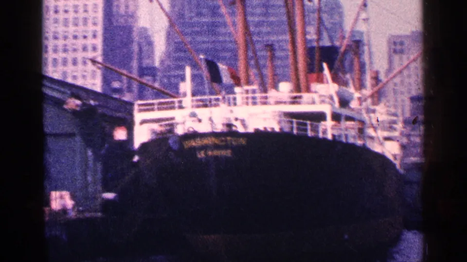 1964 New York City harbor view with a dark docked ship marked WASHINGTON and skyline buildings behind it.