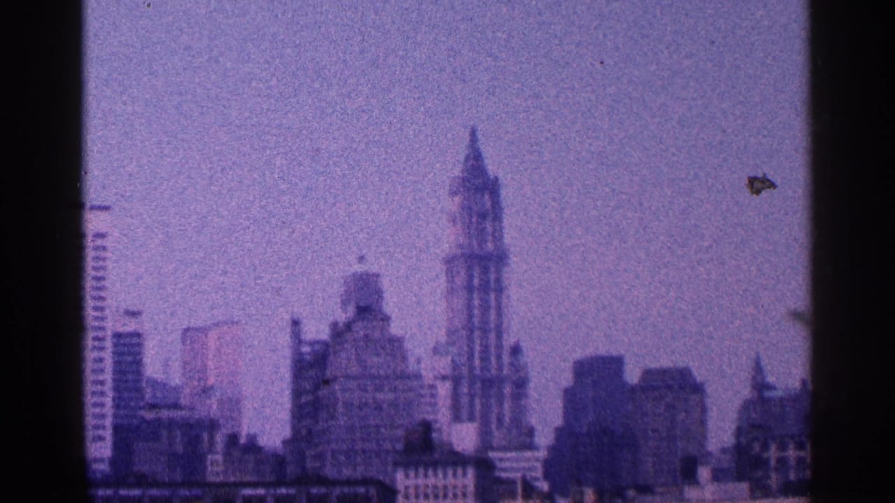 Hazy lower Manhattan skyline with the Woolworth Building spire visible.