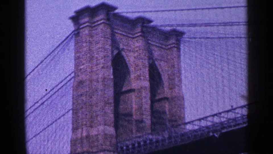 1964 New York City home-movie view of a Brooklyn Bridge stone tower, cables, and Gothic arches.