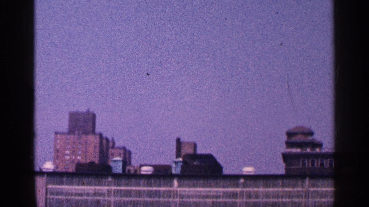 Similar rooftop skyline view with brick buildings, roof fixtures, and dark film gate edges.