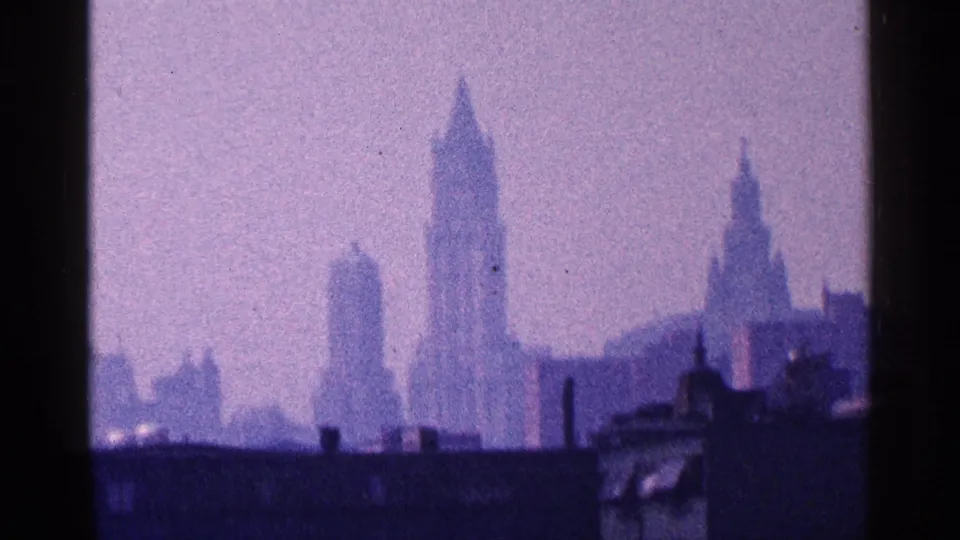New York City skyline in 1964, showing tall Manhattan buildings through haze with dark waterfront forms along the lower frame.