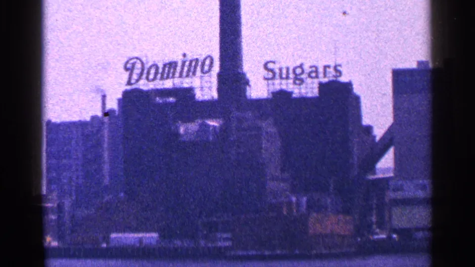 1964 New York City riverfront view of the Domino Sugars sign above industrial buildings.