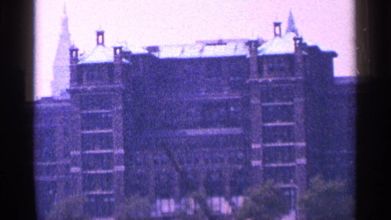 Ornate multi-story building with turrets and a pointed spire behind dark film edges.