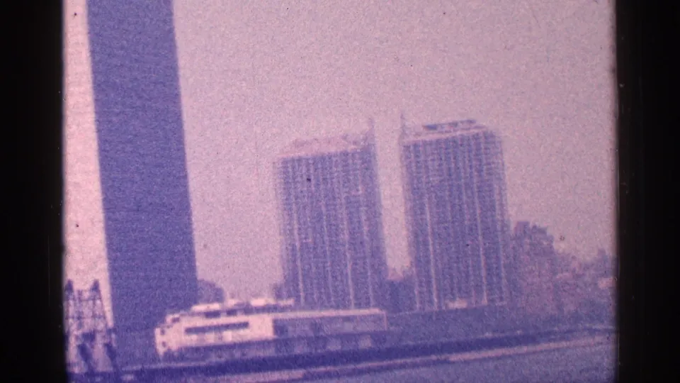 New York City landmark skyline with the United Nations Secretariat and nearby waterfront buildings in pink-purple 8mm footage.
