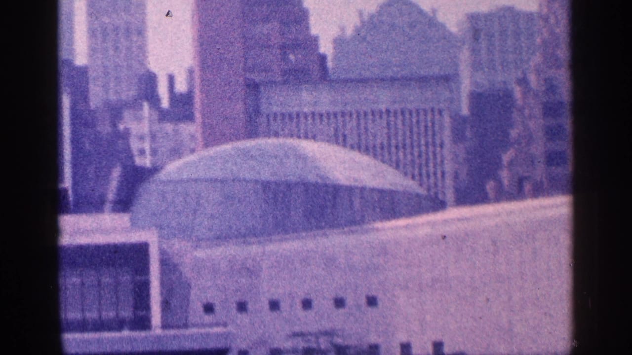 Domed rooftop building and surrounding skyscrapers seen through a purple 8mm frame.
