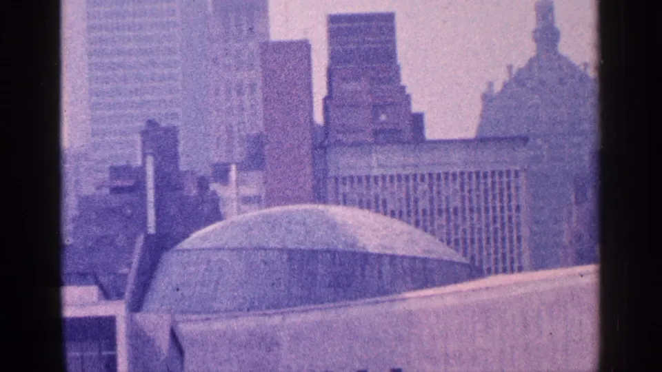 1964 New York City elevated view with a domed structure, concrete roofline, and stacked office towers in soft focus.