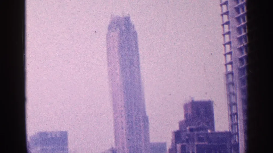 New York City skyline frame with a tall narrow skyscraper isolated against pale sky and darker buildings at the edges.