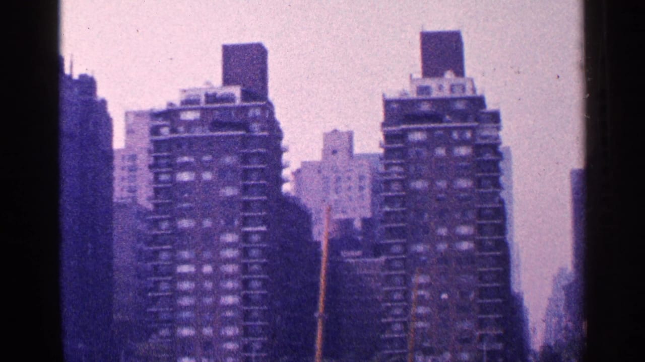 1964 New York City home-movie frame showing two high-rise apartment buildings with a faded purple color cast.