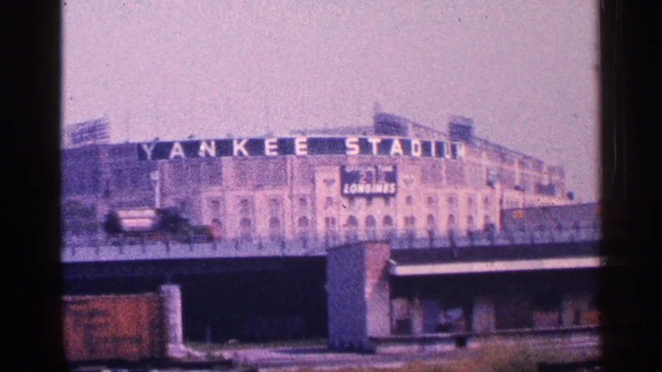 1964 New York City view of Yankee Stadium signage and facade, filmed from a distance with traffic crossing the lower frame.
