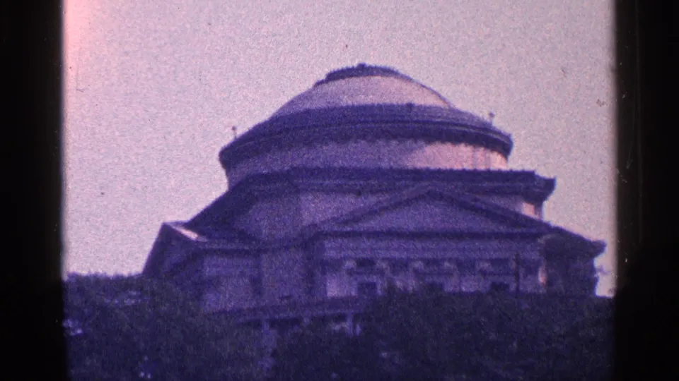1964 home-movie frame showing a large domed classical building, tinted purple and softly focused within the 8mm frame.