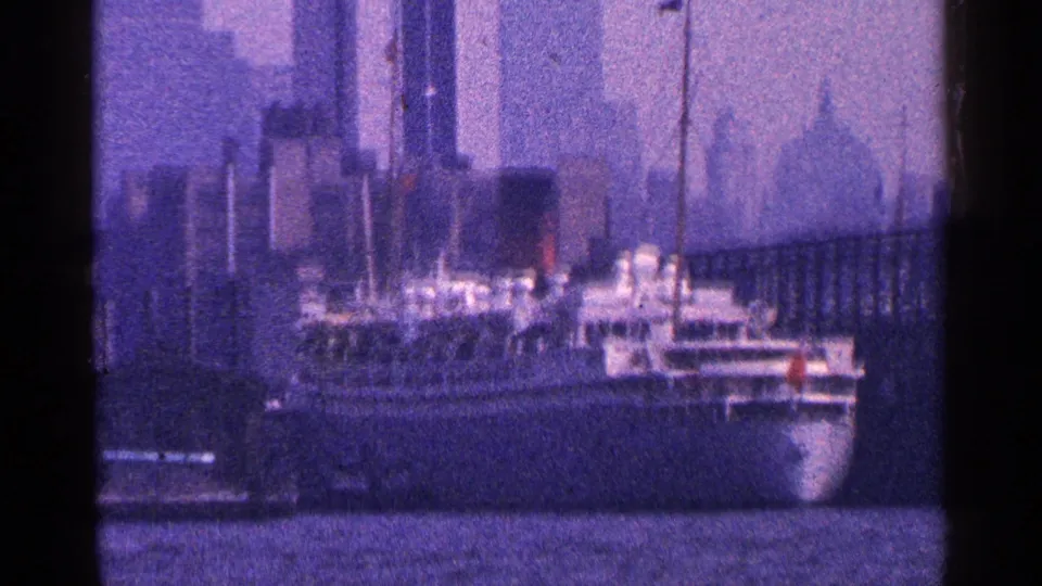 New York City waterfront frame from 1964 showing a large passenger ship against a hazy skyline and harbor water.