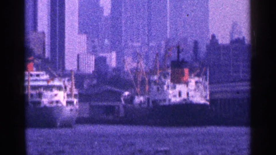 1964 New York City port view with docked ships, cranes, harbor water, and a soft skyline in the background.