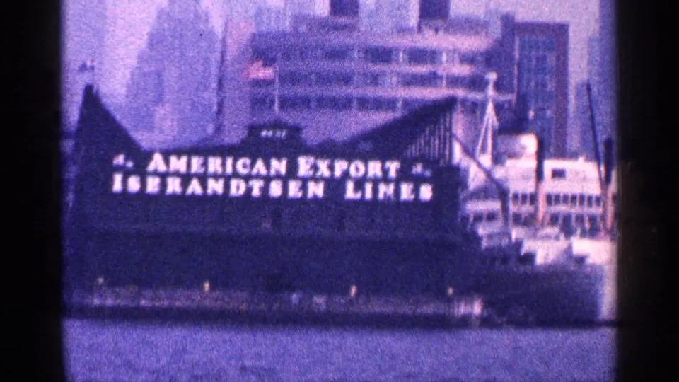 Side view of a cargo ship in New York City harbor with American Export Isbrandtsen Lines lettering visible on the hull.