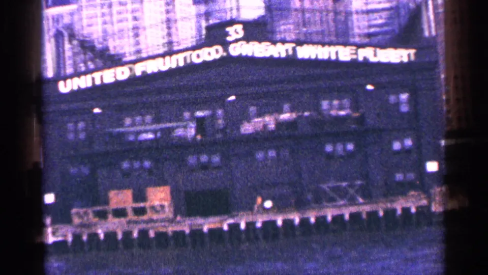 Closer 1964 New York City view of the illuminated United Fruit Co. Great White Fleet sign above a waterfront structure.