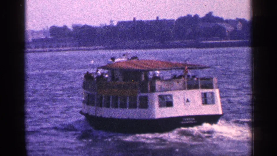 1964 New York City harbor footage showing a small passenger ferry crossing the water and leaving a wake.