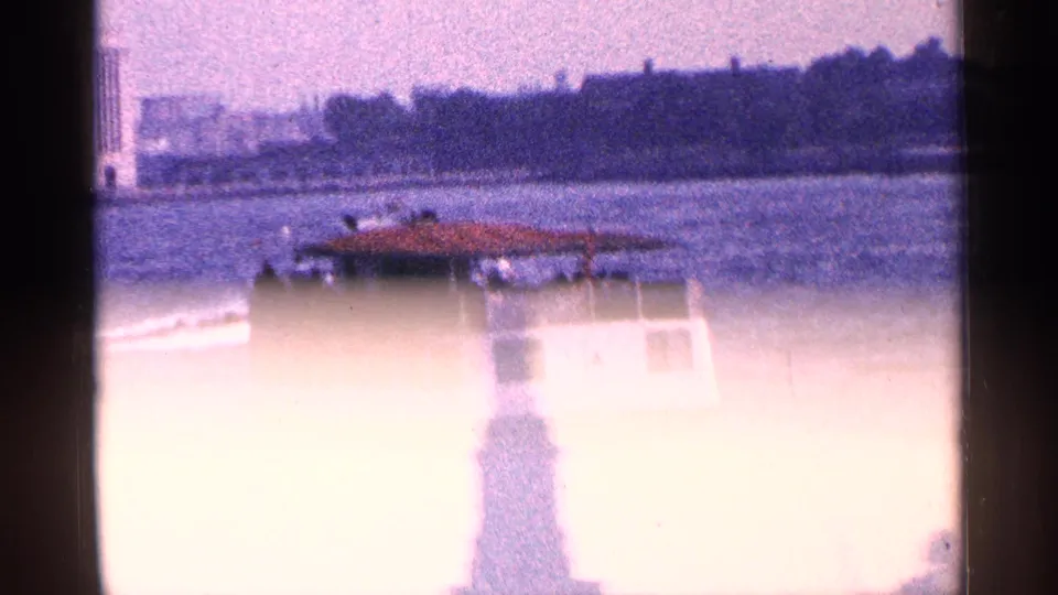 New York harbor frame with a ferry passing behind a bright, overexposed silhouette of the Statue of Liberty.