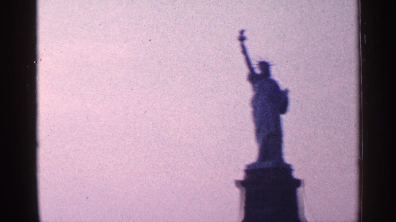 1964 8mm New York City frame with the Statue of Liberty silhouetted from a second angle, bordered by the dark edge of the film frame.