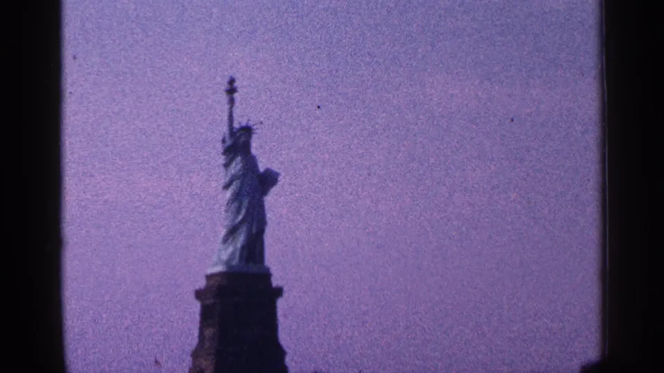 1964 8mm New York City frame with the Statue of Liberty centered on its pedestal, rendered in soft grain and purple-blue color shift.