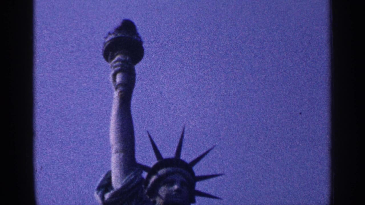 Low-angle view of the Statue of Liberty torch, arm, and crown against a dark blue-purple sky.