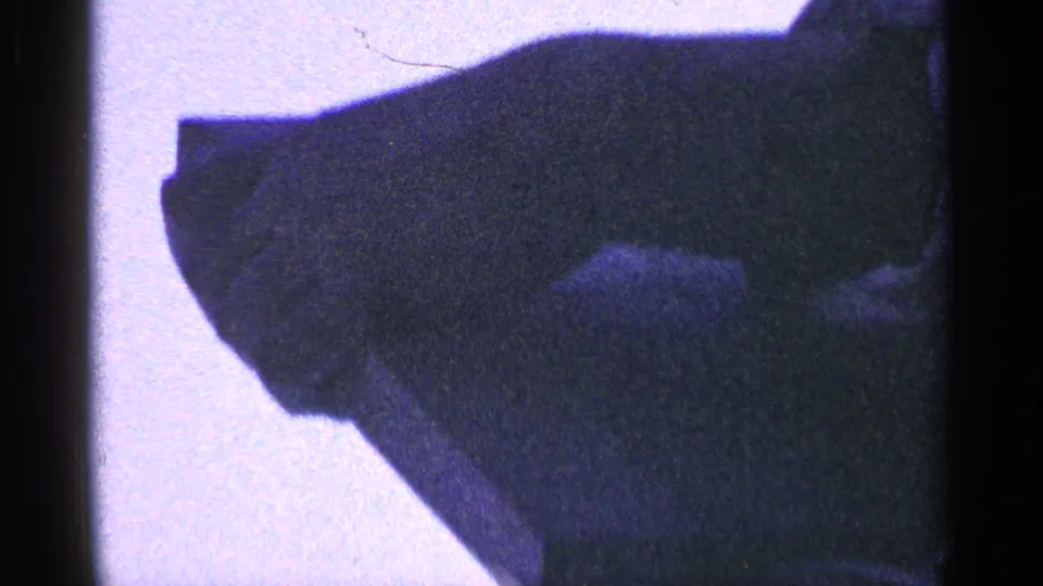 1964 New York home-movie frame with a man mostly in silhouette, framed close and partially obscured by underexposure.