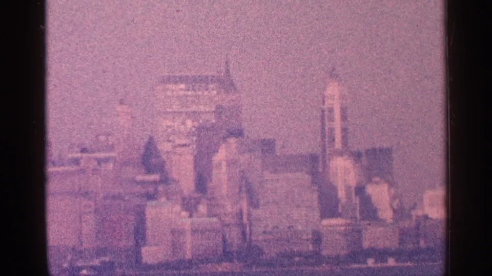 1964 New York City home-movie skyline view, showing distant tall buildings softened by haze, grain, and faded color.