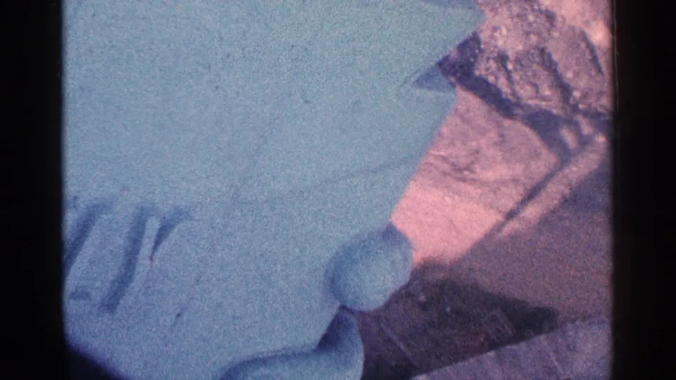 Close, washed-out 8mm frame with a partial patterned shirt, pale foreground surface, and color-shifted exposure.