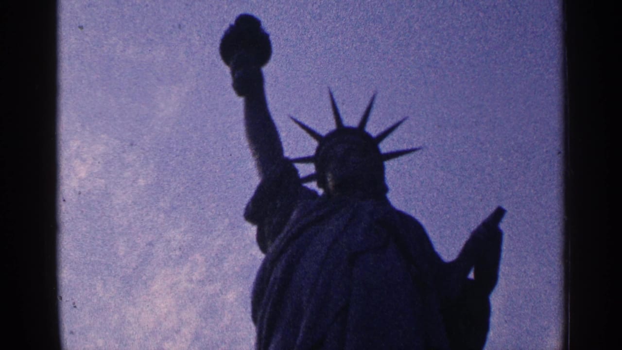 Statue of Liberty in dark silhouette against a cloudy sky.