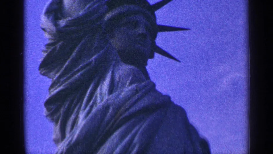 1964 New York City 8mm frame showing a close low-angle view of the Statue of Liberty head, crown, and draped robe.