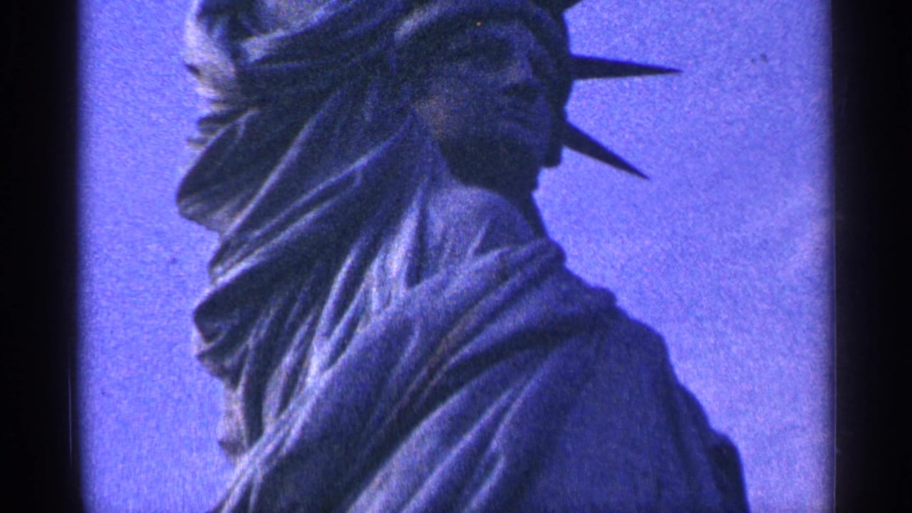 1964 8mm New York City home-movie frame showing a close view of the Statue of Liberty's face, crown spikes, and draped shoulder against a blue sky.