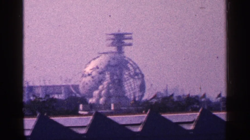 1964 New York City 8mm frame showing the Unisphere at Flushing Meadows-Corona Park beyond rooflines.