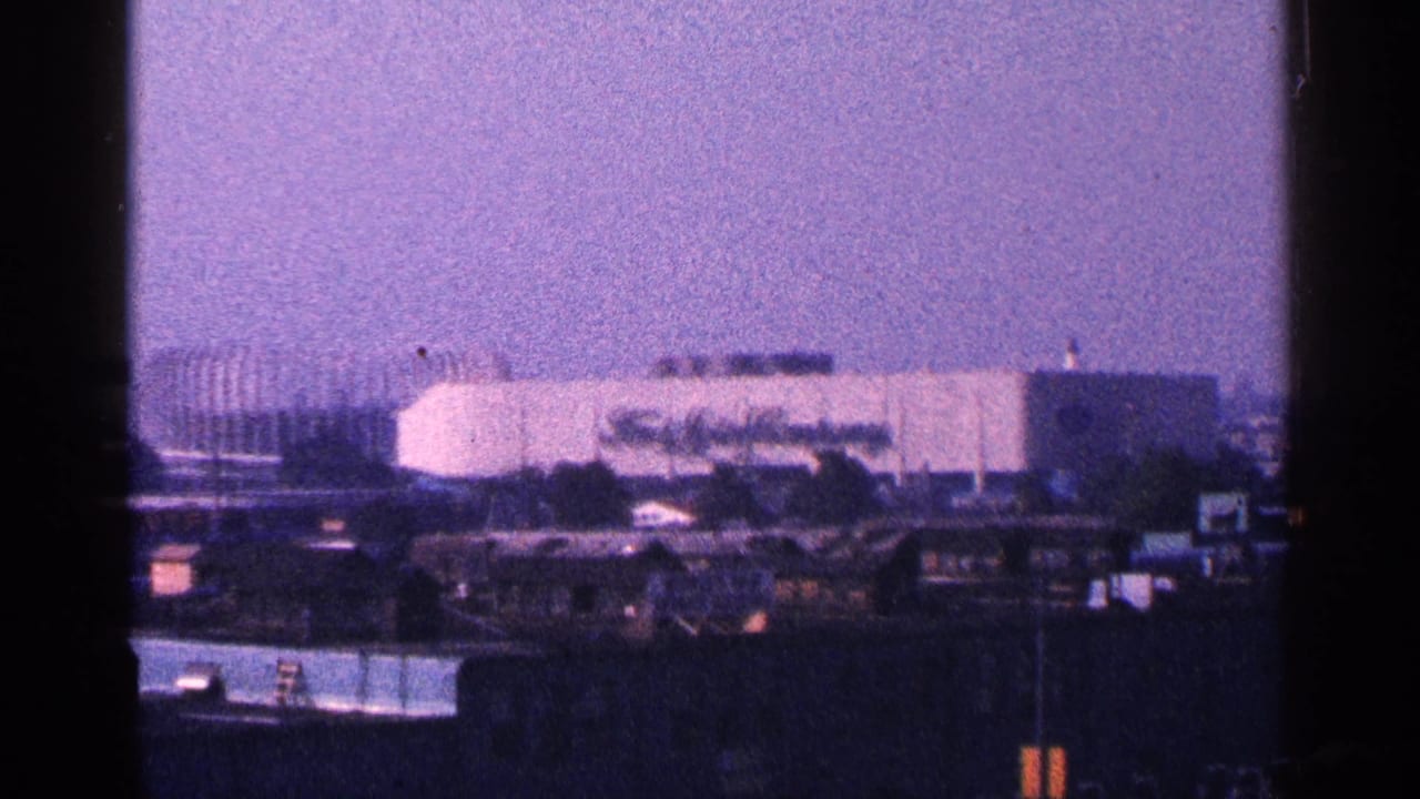 Distant hazy view of a large pale building complex beyond low foreground structures.