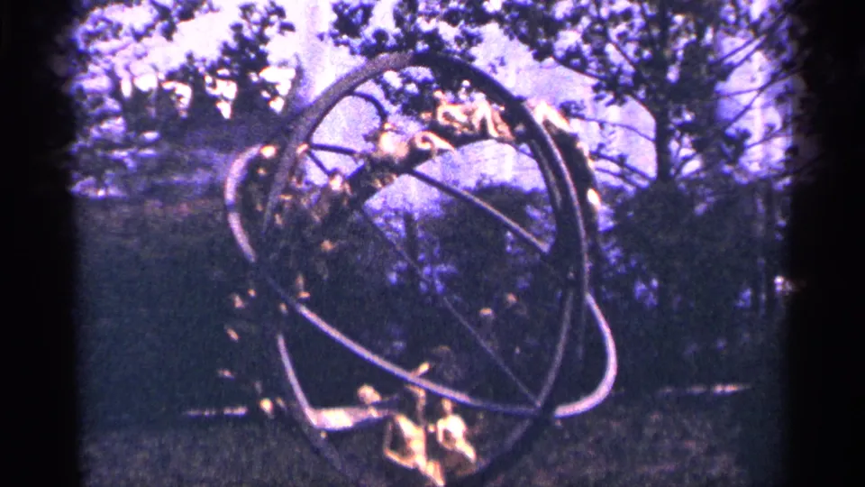 1964 8mm park view in New York City showing a ringed metal sculptural form against trees and grass.
