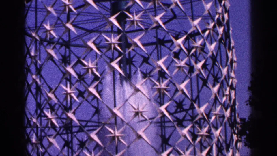 1964 New York City 8mm view of the glowing geometric fountain lattice with water spray visible through the metal pattern.